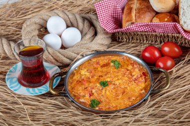 Famous Turkish menemen dinner on table, made by eggs, pepper and tomatoes. Traditional turkish food menemen made by eggs and tomatoes, tea concept background.