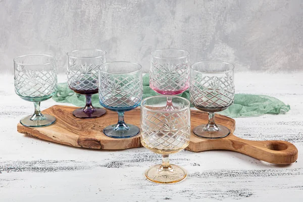 Set of six crystal juice glasses. A set of six vintage, multicolored, crystal glasses with a white stem on a light background.