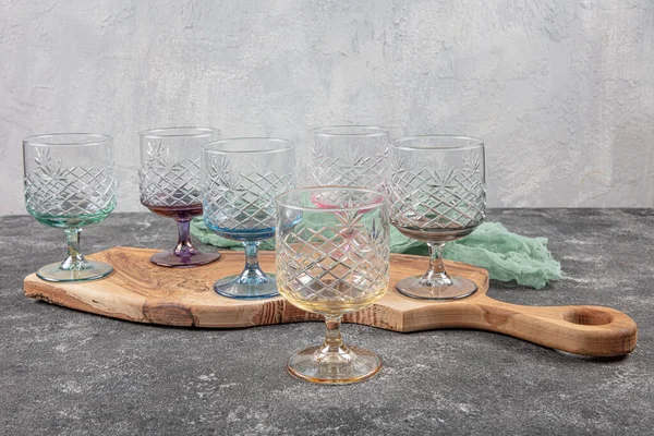 Set of six crystal juice glasses. A set of six vintage, multicolored, crystal glasses with a white stem on a light background.