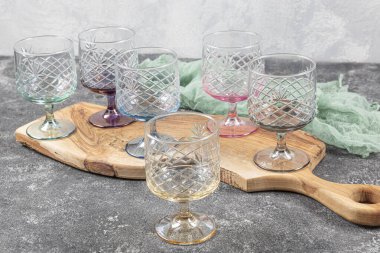 Altı kristal meyve suyu bardağı seti. Açık arkaplanda beyaz saplı, çok renkli, kristal bir gözlük seti..