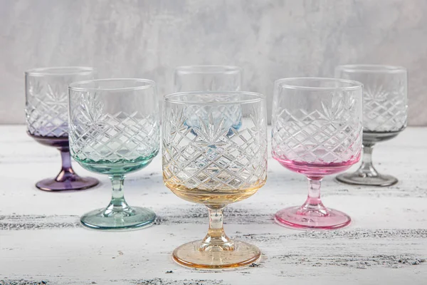 Set of six crystal juice glasses. A set of six vintage, multicolored, crystal glasses with a white stem on a light background.