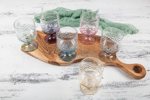 Set of six crystal juice glasses. A set of six vintage, multicolored, crystal glasses with a white stem on a light background.
