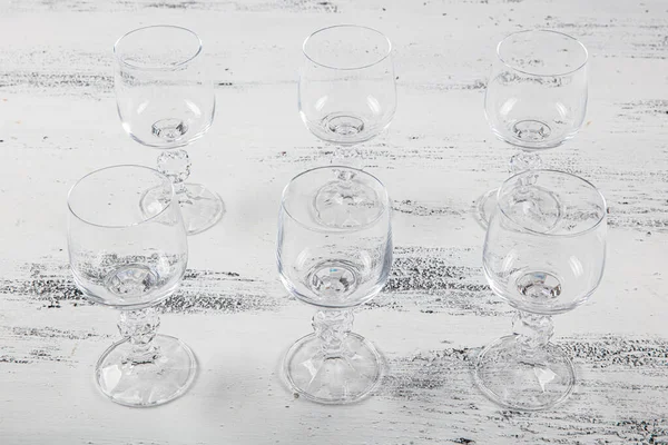 Six Crystal goblet. Set of six empty wine glasses on white wooden background.