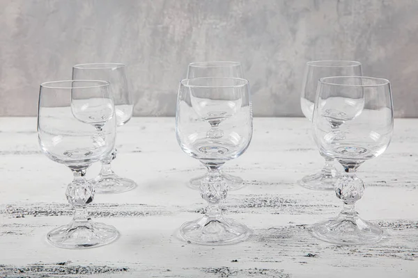 Altı Kristal Kadeh. Beyaz ahşap arka planda altı boş şarap kadehi..