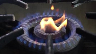 Mutfakta mavi ve kırmızı alevli siyah gaz sobası. Doğal gaz açığı kavramı. 4k çözünürlük videosu.