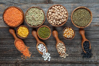 Vegan protein source.Various assortment of legumes, lentils, chickpea and beans assortment in different bowls on wooden table. Top view.