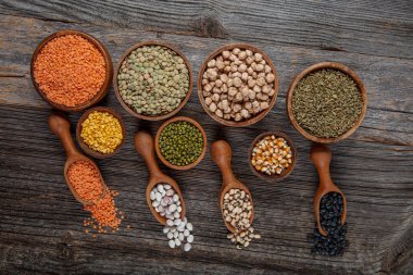 Vegan protein source.Various assortment of legumes, lentils, chickpea and beans assortment in different bowls on wooden table. Top view.