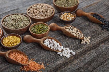 Vegan protein source.Various assortment of legumes, lentils, chickpea and beans assortment in different bowls on wooden table. Top view.