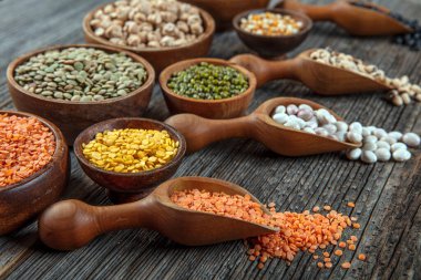 Vegan protein source.Various assortment of legumes, lentils, chickpea and beans assortment in different bowls on wooden table. Top view.
