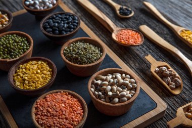 Vegan protein source.Various assortment of legumes, lentils, chickpea and beans assortment in different bowls on wooden table. Top view.