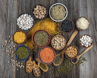 Vegan protein source.Various assortment of legumes, lentils, chickpea and beans assortment in different bowls on wooden table. Top view.
