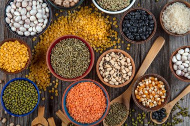 Vegan protein source.Various assortment of legumes, lentils, chickpea and beans assortment in different bowls on wooden table. Top view.