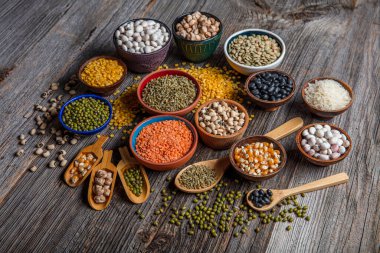 Vegan protein source.Various assortment of legumes, lentils, chickpea and beans assortment in different bowls on wooden table. Top view.