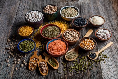 Vegan protein source.Various assortment of legumes, lentils, chickpea and beans assortment in different bowls on wooden table. Top view.