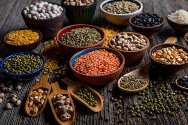 Vegan protein source.Various assortment of legumes, lentils, chickpea and beans assortment in different bowls on wooden table. Top view.