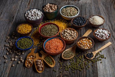 Vegan protein source.Various assortment of legumes, lentils, chickpea and beans assortment in different bowls on wooden table. Top view.