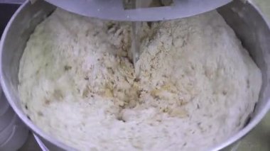 Pasta hamuru yapmak. Makine ekmek hamuru yoğurur. Endüstriyel fırın hamur karıştırıcısında çiğ hamur, gıda konsepti. Stok görüntüleri. 4K çözünürlük videosu.