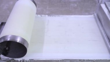 Otomatik hamur makinesiyle fillo hamur yapma işlemi. Bir gıda üretim tesisinde fillo hamuru için çarşaf yapıyorum. Ev yapımı hamur makası ve sedye. 4k video.