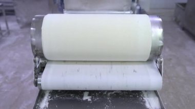 Otomatik hamur makinesiyle fillo hamur yapma işlemi. Bir gıda üretim tesisinde fillo hamuru için çarşaf yapıyorum. Ev yapımı hamur makası ve sedye. 4k video.