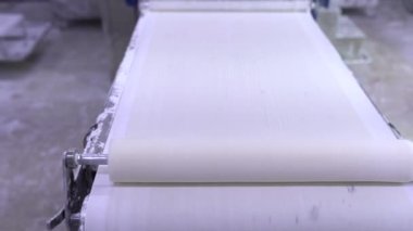Otomatik hamur makinesiyle fillo hamur yapma işlemi. Bir gıda üretim tesisinde fillo hamuru için çarşaf yapıyorum. Ev yapımı hamur makası ve sedye. 4k video.