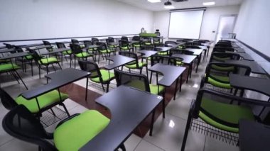 Yeşil sandalyeli ve boş ekranlı bir sunum odasının minimalist iç mekanı. Konferans odasının içinde. Konferans ve sunum konsepti. 4K Video.