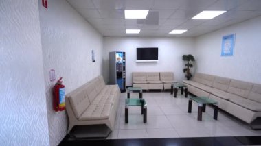 Beyaz mermer zemin üzerinde duvar süsleme satış galerisi olan resepsiyon bekleme salonu ve sandalyeli masa. video 