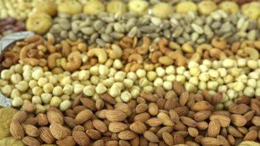 Kamera fındık makro çekim üzerinden hareket ediyor. Çeşitli fındıklar yaklaşıyor. ceviz, badem, fındık ve diğer fındıklar masada kurutulur. Yüksek kalorili vejetaryen yemeği. Kuru fındık. 4K Video.