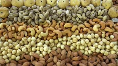 Kamera fındık makro çekim üzerinden hareket ediyor. Çeşitli fındıklar yaklaşıyor. ceviz, badem, fındık ve diğer fındıklar masada kurutulur. Yüksek kalorili vejetaryen yemeği. Kuru fındık. 4K Video.