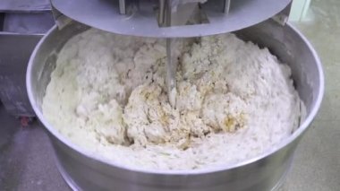 Pasta hamuru yapmak. Makine ekmek hamuru yoğurur. Endüstriyel fırın hamur karıştırıcısında çiğ hamur, gıda konsepti. Stok görüntüleri. 4K çözünürlük videosu.