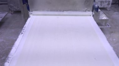 Otomatik hamur makinesiyle fillo hamur yapma işlemi. Bir gıda üretim tesisinde fillo hamuru için çarşaf yapıyorum. Ev yapımı hamur makası ve sedye. 4k video.