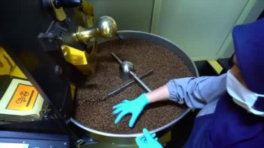 Kavrulmuş kahve çekirdekleri soğutucudan düşer. Arabika fasulyeleri dökülür ve döndürülürler. Endüstriyel kızartma ve üretim, kahve endüstrisi. Yakından bakınca, kahverengi taneler paketlere doldurulmak için dökülüyor..