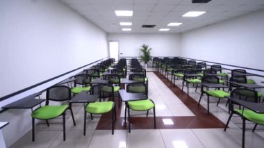 Yeşil sandalyeli ve boş ekranlı bir sunum odasının minimalist iç mekanı. Konferans odasının içinde. Konferans ve sunum konsepti. 4K Video.