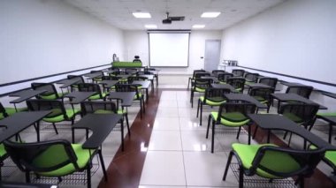 Yeşil sandalyeli ve boş ekranlı bir sunum odasının minimalist iç mekanı. Konferans odasının içinde. Konferans ve sunum konsepti. 4K Video.