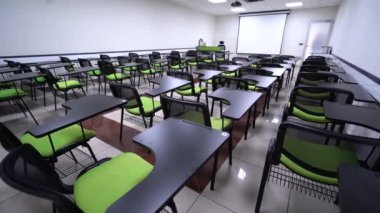 Yeşil sandalyeli ve boş ekranlı bir sunum odasının minimalist iç mekanı. Konferans odasının içinde. Konferans ve sunum konsepti. 4K Video.