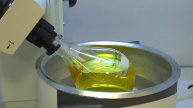 Rotavapor adı tanımlayıcı buharlaştırıcı üzerinde çalışan kimya bilimcisi. Laboratuvardaki deney sırasında buharlaştırıcıyı kontrol eden bilimadamı. Makinenin dönen bir matarası var. Video.