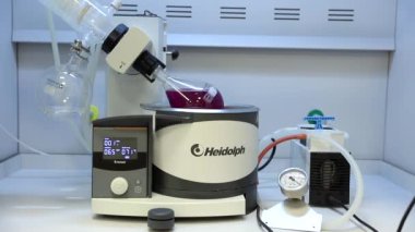 Rotavapor adı tanımlayıcı buharlaştırıcı üzerinde çalışan kimya bilimcisi. Laboratuvardaki deney sırasında buharlaştırıcıyı kontrol eden bilimadamı. Makinenin dönen bir matarası var. Video.