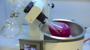 Rotavapor adı tanımlayıcı buharlaştırıcı üzerinde çalışan kimya bilimcisi. Laboratuvardaki deney sırasında buharlaştırıcıyı kontrol eden bilimadamı. Makinenin dönen bir matarası var. Video.