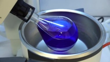 Rotavapor adı tanımlayıcı buharlaştırıcı üzerinde çalışan kimya bilimcisi. Laboratuvardaki deney sırasında buharlaştırıcıyı kontrol eden bilimadamı. Makinenin dönen bir matarası var. Video.