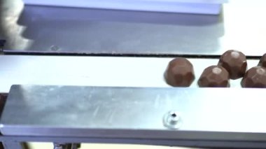 Bir çikolata fabrikasının konveyöründe makine tarafından üretilen çikolatalar için çeşitli malzemeler. Bu fotoğraf, ambalaj yaparken çikolata fabrikasında çalışan bir işçi için çekildi. 4K video.