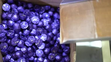 Bir çikolata fabrikasının konveyöründe makine tarafından üretilen çikolatalar için çeşitli malzemeler. Bu fotoğraf, ambalaj yaparken çikolata fabrikasında çalışan bir işçi için çekildi. 4K video.