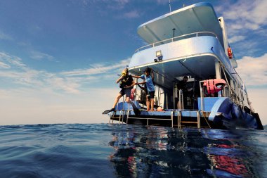 Scuba dalgıcı suya dev bir adımla giriyor. Bir dalış teknesinden.