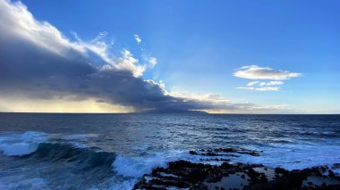Fırtınalı bulutlarla okyanusun üzerinde dramatik bir gökyüzü.