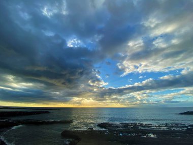 Plaj gündoğumu tropikal denizin üzerinde, dramatik bulutlar okyanusun üzerinde. 