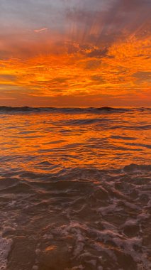 İnanılmaz turuncu gün batımı ve dramatik gökyüzü olan bulutlar ya da deniz ve okyanus dalgaları üzerinde gün doğumu. Güzel doğa minimalist arka plan ve doku Panoramik doğa manzarası dramatik ışık gökyüzü ve bulutlar.