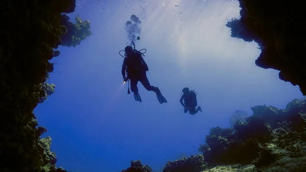 Underwater photo of a scuba divers in beautiful light inside a cave.