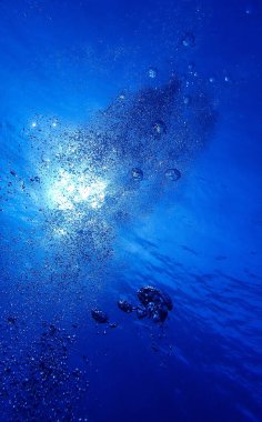 Hava kabarcıkları güneş ışınlarıyla yüzeye çıkıyor. Su altı fotoğraf sanatı.