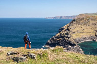 Adam arkası dönük duruyor ve önüne bakıyor. Cornwall, Boscastle, İngiltere 'de güzel okyanus manzarası.