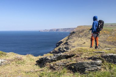 Adam arkası dönük duruyor ve önüne bakıyor. Cornwall, Boscastle, İngiltere 'de güzel okyanus manzarası.