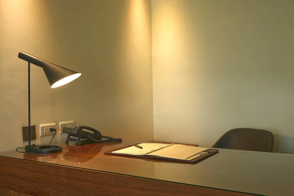 Lamp, phone and note book on a desk in a luxury office