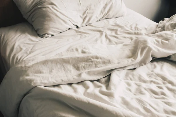 Yastıklı dağınık yatak, beyaz çarşaf..